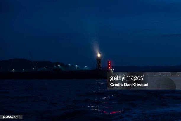 The lighthouse beams out from the Dover Port harbour wall at dawn on August 24, 2023 The English Channel, England. Several boats carrying migrants...