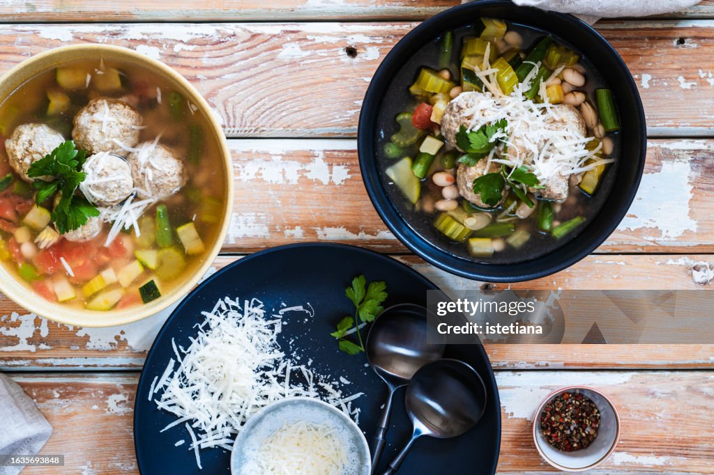 Minestrone soup with seasonal summer vegetables, meatballs, and parmesan cheese, high angle view