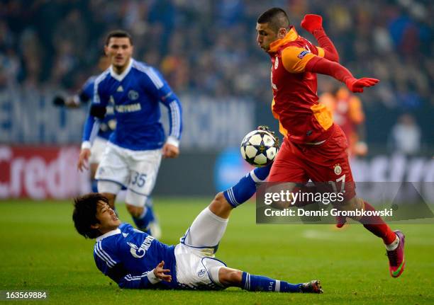 Atsuto Uchida of Schalke challenges Burak Yilmaz of Galatasaray during the UEFA Champions League round of 16 second leg match between Schalke 04 and...