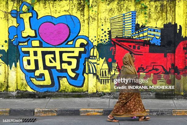 Woman walks past a wall mural reading 'I love Mumbai' along a street in Mumbai on August 31, 2023.