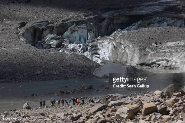 Visitors stand before the collapsed face of the Pasterze, Austria's biggest glacier, and a lake of meltwater at the end of the glacier tongue on...