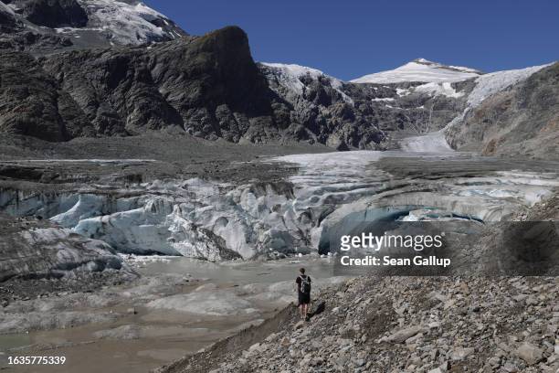 Hiker stands in front of the collapsed face of the Pasterze, Austria's biggest glacier, at the end of the glacier tongue on August 21, 2023 near...