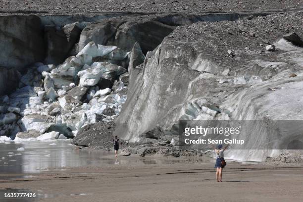 Visitors walk in front of the collapsed face of the Pasterze, Austria's biggest glacier, at the end of the glacier tongue on August 21, 2023 near...