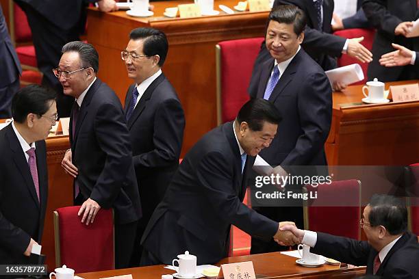 Former chairman of the Chinese People's Political Consultative Conference Jia Qinglin shakes hands with the newly-appointed chairman of the CPPCC Yu...