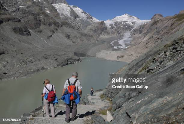 Two elderly hikers descend from a spot where in 1960 the Pasterze, Austria's biggest glacier, stood, both in length and height, as the glacier face...