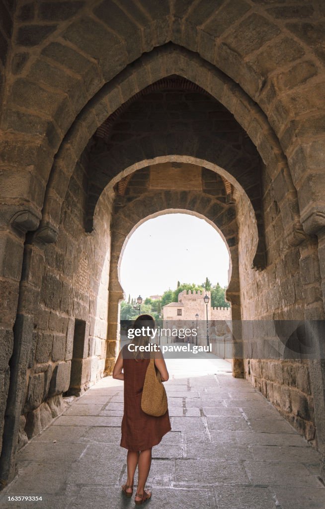 Woman looking at city gate and San Martin's Bridge, Toledo city Spain