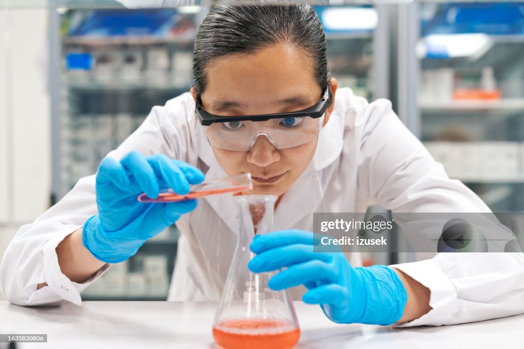 実験室で働きながらビーカーに化学物質を注ぐ集中した女性科学者