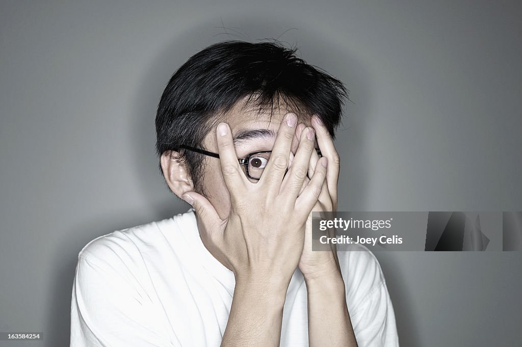 Asian male covering his face with his hands