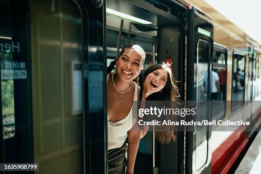 Young women looking out of the train door Young women looking out of the train door