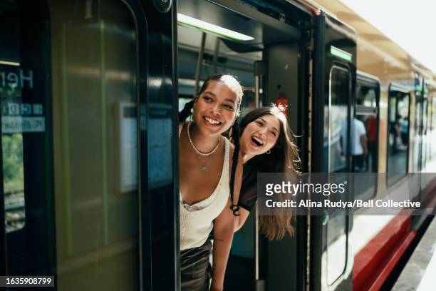 young women looking out of the train door - travel fotografías e imágenes de stock