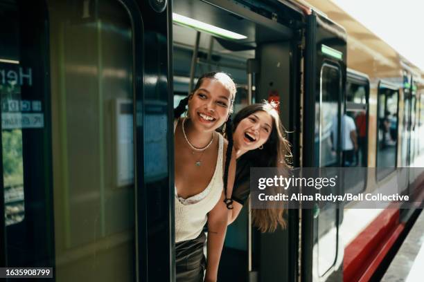 young women looking out of the train door - métro train de voyageurs photos et images de collection