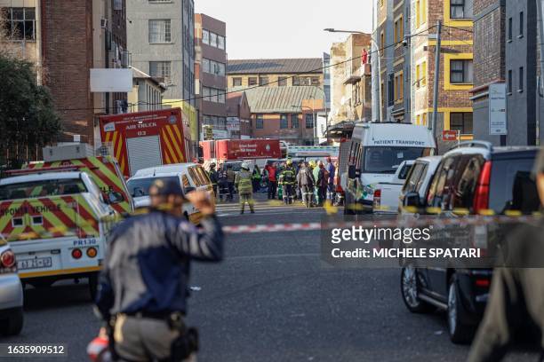 South African firefighters and South African Police Service officers work at the sceen of a fire in Johannesburg on August 31, 2023. At least 20...