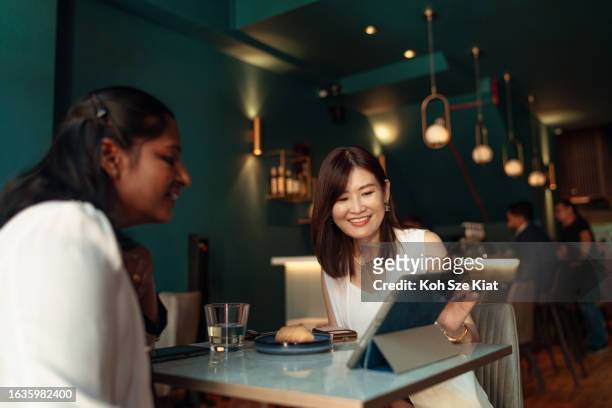 indische und chinesische berufstätige mittleren alters in einer arbeitsbesprechung in einem restaurant - indian lunch stock-fotos und bilder