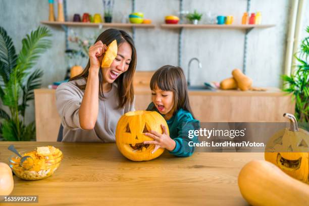 getting ready for halloween - asian mother and daughter pumpkin stockfoto's en -beelden