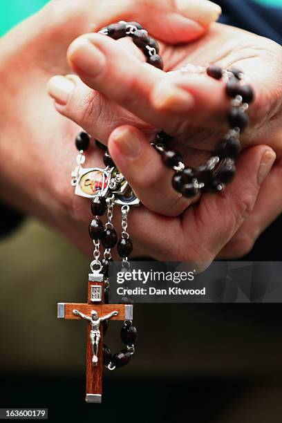 Woman holds rosary beads while she prays and waits for smoke to emanate from the chimney on the roof of the Sistine Chapel which will indicate...