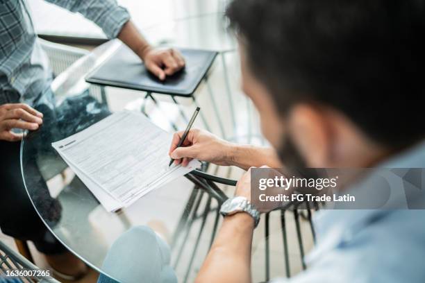 nahaufnahme eines männlichen kunden, der zu hause einen vertrag mit einem finanzberater unterzeichnet - unterschrift stock-fotos und bilder
