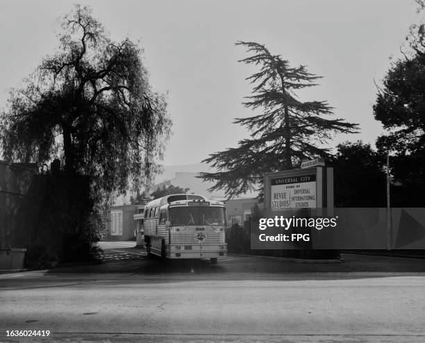 Gray Line' studio tour coach passes a sign reading 'Universal City - Home of Revue Studios, Universal International Studios' as it leaves Universal...