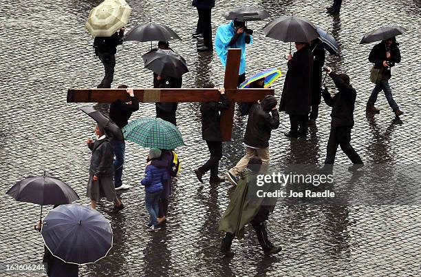 People carry a cross through St Peter's Square as they wait for news on the election of a new Pope on March 13, 2013 in Vatican City, Vatican. Pope...