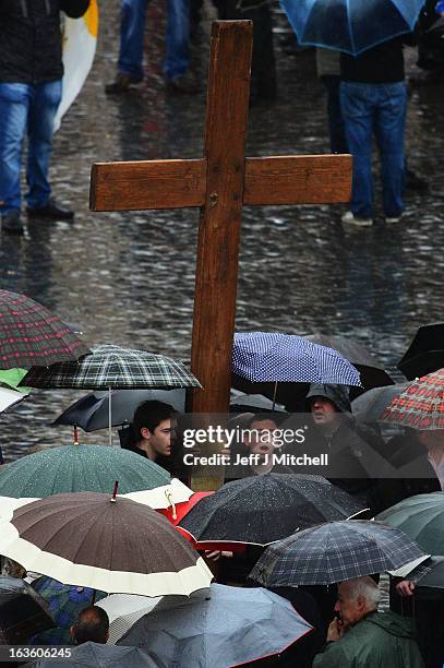 Pilgrims carry a large cross through St Peter's Square as they wait for news on the election of a new Pope on day two of the conclave on March 13,...