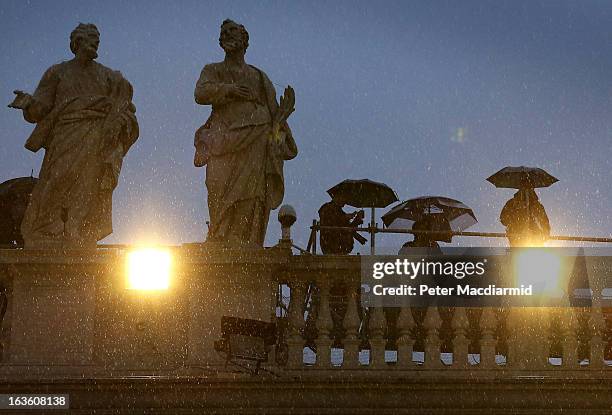 Members of the press use umbrellas to shelter from the rain on the colonade of St Peter's Square on March 13, 2013 in Vatican City, Vatican. Pope...