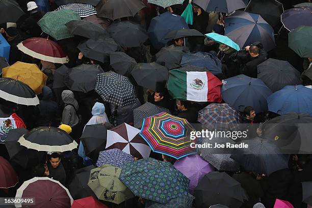 People shelter from the rain under umbrellas as they gather in St Peter's Square for news on the election of a new Pope on March 13, 2013 in Vatican...