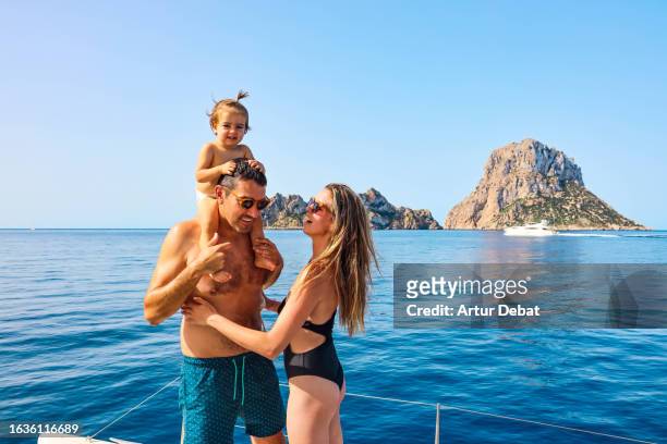 happy family with father carrying baby girl on shoulders enjoying vacations sailing on private catamaran deck on ibiza island. - es vedra stock pictures, royalty-free photos & images