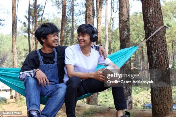two young man relaxing on hammock - young man listening music and relaxing in hammock stock pictures, royalty-free photos & images