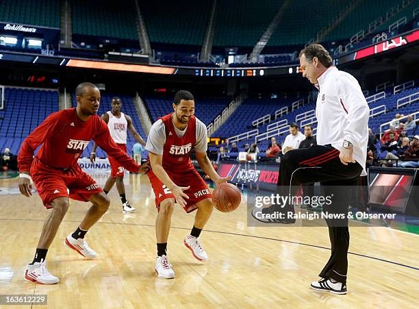 North Carolina State's Mark Gottfried, right, kicks the ball to Jay Lewis, center, as Lorenzo Brown guards him during the Wolfpack's open practice...