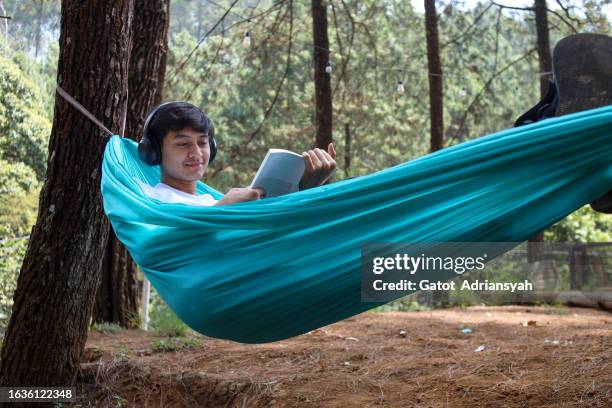 reading book on hammock - young man listening music and relaxing in hammock stock pictures, royalty-free photos & images