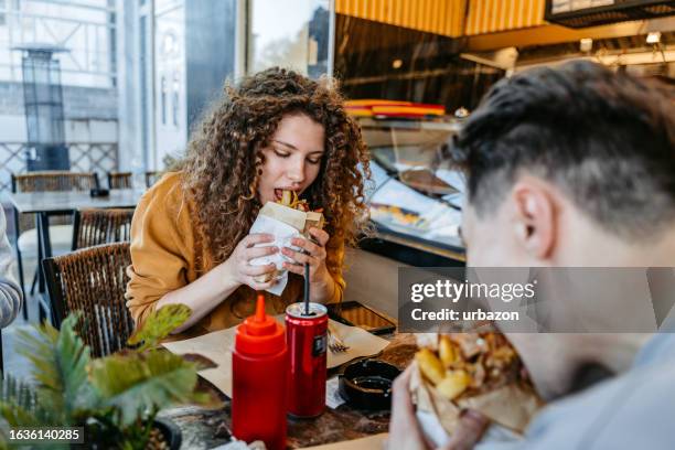 young woman eating gyros with her boyfriend at a diner - doner kebab stock pictures, royalty-free photos & images