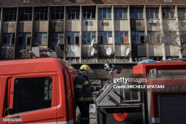 South African firefighter standing on a fire engine looks on at the scene of a fire in Johannesburg on August 31, 2023. More than 60 people have died...