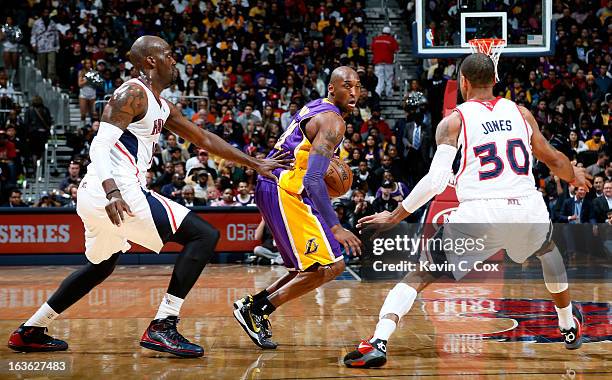 Johan Petro and Dahntay Jones of the Atlanta Hawks defend against Kobe Bryant of the Los Angeles Lakers at Philips Arena on March 13, 2013 in...