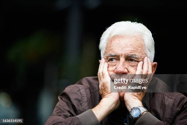 elderly man sits, head in hands, looking unhappy and thoughtful - sour faced stock pictures, royalty-free photos & images