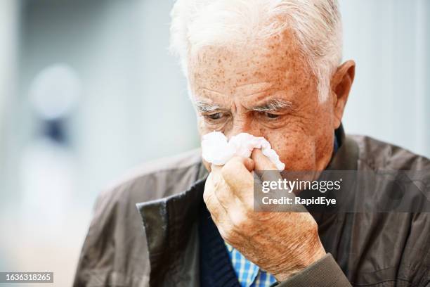 elderly man blowing his nose on a tissue in the street: he has a cold or flu - cold stock pictures, royalty-free photos & images