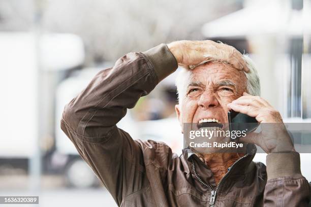 elderly man reacts as he gets bad news on his mobile phone - angry on phone stockfoto's en -beelden