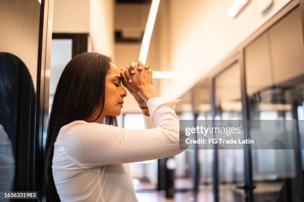 besorgte geschäftsfrau, die im büro arbeitet - frau mittleren alters stock-fotos und bilder