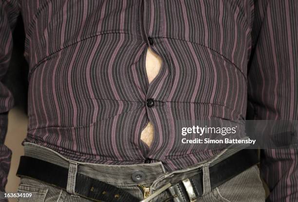 bulging stomach stretches shirt - male belly button stock pictures, royalty-free photos & images