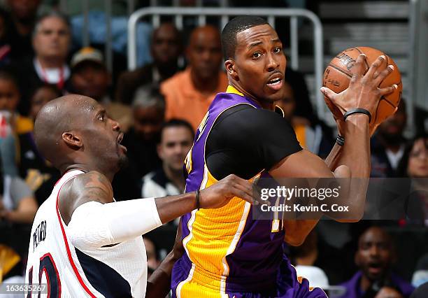 Dwight Howard of the Los Angeles Lakers controls the ball against Johan Petro of the Atlanta Hawks at Philips Arena on March 13, 2013 in Atlanta,...