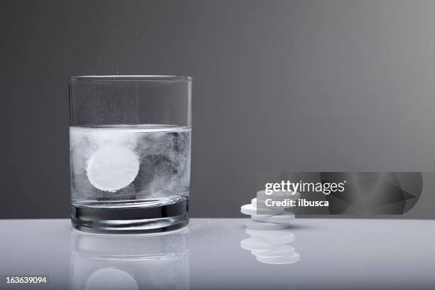 aspirin paracetamol pill splashing into glass of water - pijnstiller stockfoto's en -beelden