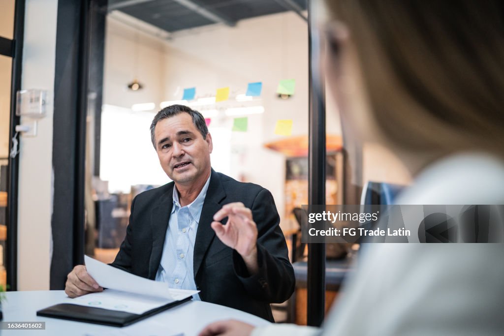 Mature businessman talking to coworkers on a meeting at office