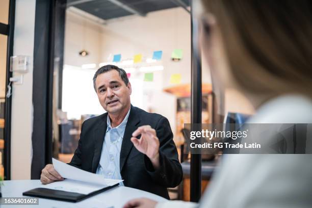 mature businessman talking to coworkers on a meeting at office - meeting candid office suit stock pictures, royalty-free photos & images