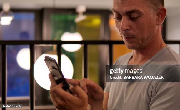Yevgen Kuruch, 38-years-old Ukrainian reserve officer and now taxi driver, uses his mobile phone as he sits in a café in Warsaw, Poland, on July 31,...