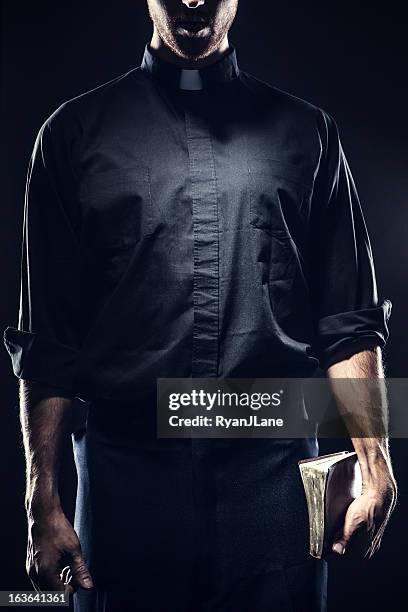 catholic priest holding a bible - priest stockfoto's en -beelden