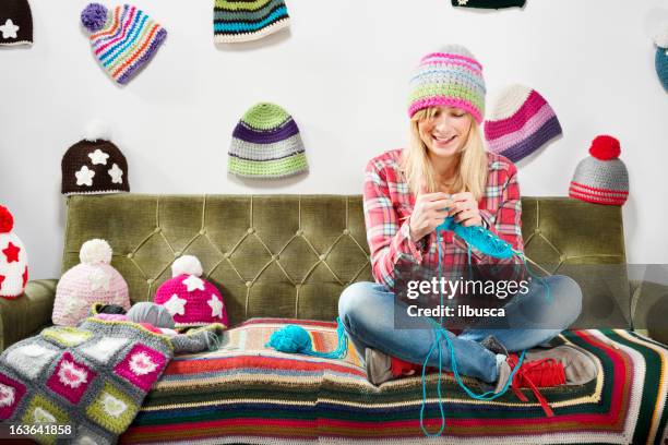 jeune femme tricotant sur un canapé avec bonnets de laine - tricoter photos et images de collection