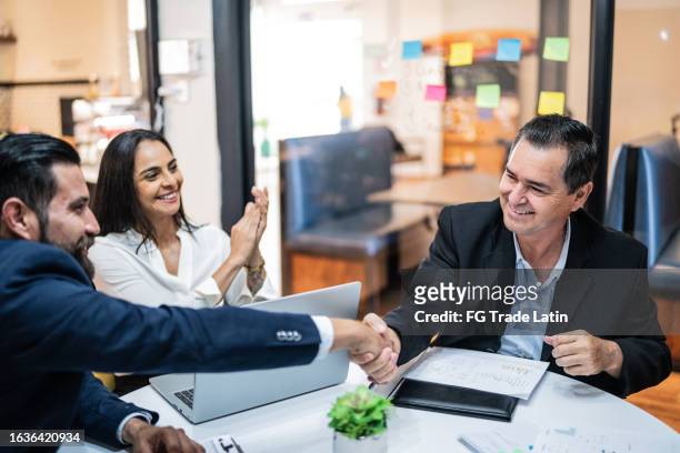 mature businessman handshake a coworker on a business meeting at office - closing sale stock pictures, royalty-free photos & images