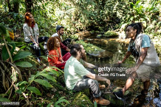 guide touristique expliquant à un groupe d’amis lors d’une randonnée en forêt - tourisme vert photos et images de collection