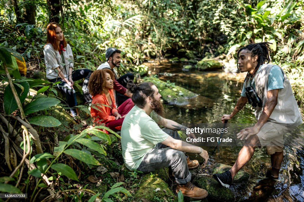 Tourist guide explaining to a group of friends during hiking in the forest
