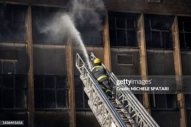 Firefighter extinguishes a fire in an apartment block in Johannesburg on August 31, 2023. More than 70 people have died in a fire that engulfed a...