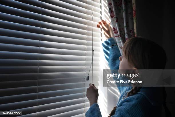 child opening blinds across a bedroom window to let the springtime morning light in. - alpha female stock pictures, royalty-free photos & images