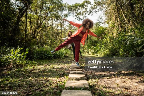 young women walking on stones during hiking in the forest - op een been staan stockfoto's en -beelden
